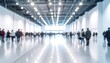 © Yasing - Blurred view of a busy, brightly lit convention center hall with many indistinct figures.