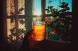 © aboutnuylove - A glass of orange tea in the hands of a girl near the window.