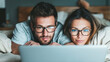 © Bonsales - Couple wearing glasses relaxing in bed watching laptop together, enjoying online streaming at home