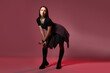 © New Africa - Beautiful young woman with piercings in stylish skirt and boots posing in red light on pink background