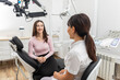 © Maria - Female dentist talking to a young patient during appointment in modern dental clinic before teeth treatment