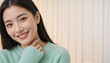 © Vyatcheslav - Smiling young East Asian woman in a green knitted sweater. Portrait of a happy female with clear skin and white teeth. Wellness and skincare concept. Copy space for text