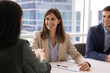 © fizkes - Middle-aged businesswoman sitting at meeting table, shaking hands with female client, exudes confidence and satisfaction, concluding negotiation successfully, making business deal in corporate office