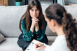 © nenetus - Shot of beautiful woman having therapy while the psychologist takes notes, sitting on the couch in the psychology office