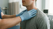 © Jai Izzam - Close up of faceless doctor in blue medical gloves examining male patient neck and collarbone in clinic