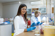 © Graphicroyalty - Portrait of smiling young female scientist in laboratory, medical research team, healthcare and medicine concept. Attractive woman lab technician sitting at desk with petri dishes and equipment.