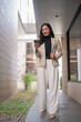 © Tj - Young businesswoman walking, using smartphone in urban setting