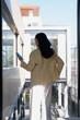 © Tj - Woman holding phone looking at city view from balcony