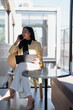 © Tj - Businesswoman talking on phone holding tablet on office balcony