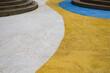 © Livia - Abstract curved outdoor pavement with white, yellow and blue painted stripes and concrete steps. Modern urban geometric background with texture, bold color contrast and copy space.