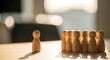 © nanang - Dramatic lighting illuminates a group of small wooden peg people huddled together, with one figure standing apart, representing leadership, individuality, or social dynamics.