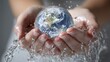 © imstock - Las manos de una mujer joven sostienen una esfera de agua que tiene el planeta tierra dibujado