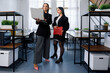 © makedonski2015 - Two businesswomen reviewing a laptop in a modern office space during the day