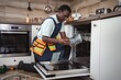 © Jelena - Technician repairing dishwasher in a modern kitchen