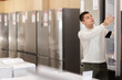 © JackF - Guy buyer examines fridge and decides on purchase. Buyer chooses exhibition hall, buys in sales area, and gets acquainted with product. Showroom of store of household appliances.