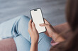 © Daniel - A millennial woman rests indoors while using her mobile phone with a mockup screen, reading updates, calling, or messaging, capturing everyday technology use in a comfortable home setting