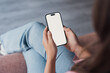 © Daniel - Close-up of a young woman relaxing at home while holding a smartphone with a blank screen, scrolling news, browsing the internet, or chatting online in a modern digital lifestyle moment