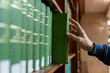 © Smallroombigdream - Hand selecting book from wooden library shelf. Legal research concept, attorney reference material, system study, academic knowledge and professional legislation archive.