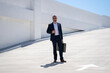 © Volodymyr - Business outdoor portrait. Business man walking outdoors. Corporate leader on move. Man in suit with briefcase. Business man going to work. Businessman with briefcase. Business man go to office.