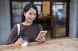 © leungchopan - Woman check phone while sitting at outdoor cafe