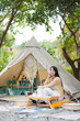 © leungchopan - Woman sit at campsite outdoors in nature