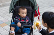 © leungchopan - Parent giving banana to baby in stroller