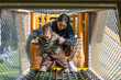 © leungchopan - Mother helping baby climb rope net at park