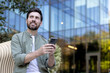© Liubomir - Young man sitting in an urban park, looking up thoughtfully while engaging with his smartphone, reflecting on future ideas or business opportunities in a digital world