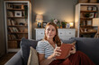 © Migma_Agency - Woman relaxing at home reading book on couch