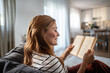 © Migma_Agency - Woman relaxing at home reading a book on sofa