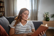 © Migma_Agency - Woman reading book relaxing on couch at home