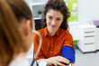 © Graphicroyalty - A young woman sits in a medical office while a healthcare professional uses a manual sphygmomanometer and stethoscope to check her blood pressure. Professional heart health monitoring and prevention.