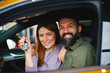 © djile - Happy couple sitting inside their new car in showroom