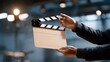 © Tania - A hand is holding a clapper board during a rehearsal, underlining the meticulous planning and rehearsals integral to achieving an engaging final product in the realm of film. cinematic color