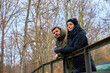 © barmaleeva - Man and woman in warm jackets standing by metal railing in park