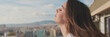 © Andrii Nekrasov - Young woman enjoying beautiful view while standing on the balcony. Panoramic