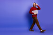 © deagreez - Young handsome man with glasses walks with a laptop against a violet background highlighting casual fashion lifestyle and education themes for advertising and promotion