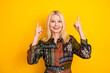 © deagreez - Happy mature woman in colorful patchwork dress pointing up against yellow background