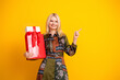 © deagreez - Beautiful mature blonde woman smiles while holding gift boxes against a bright yellow background