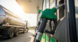 © ViskBx - Fuel pump nozzle at a gas station with a tanker truck in the background, fuel industry