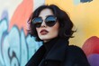 © Yuliia - A Stylish Woman Stands Out in Front of Vibrant Graffiti Wall in Urban Setting, Highlighting Her Individuality and Fashion Sense.