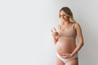 © Stock 4 You - Young woman, awaiting child mother with naked tummy belly, using smartphone cellphone application controlling pregnancy, prenatal maternity, motherhood and female health standing isolated. Copy space