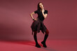 © New Africa - Beautiful young woman with piercings in stylish skirt and boots posing in red light on pink background