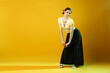 © New Africa - Beautiful young woman with piercings in wide pants in color light on yellow background. Space for text