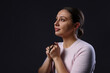 © New Africa - Woman with cross praying on black background, space for text