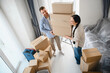 © Serhii - Happy couple carrying cardboard boxes moving into new home