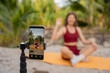 © Aleksej - Woman recording fitness workout on smartphone outdoors in tropical setting