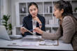 © Apichat - Business women discussing report data during office meeting