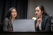 © Apichat - Businesswomen collaborating on laptop in dark office at night