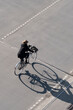 © yaqui_villegas - Urban cyclist on bicycle commuting on street with strong shadow showing sustainable mobility in Copenhagen Denmark with minimal overhead perspective and motion